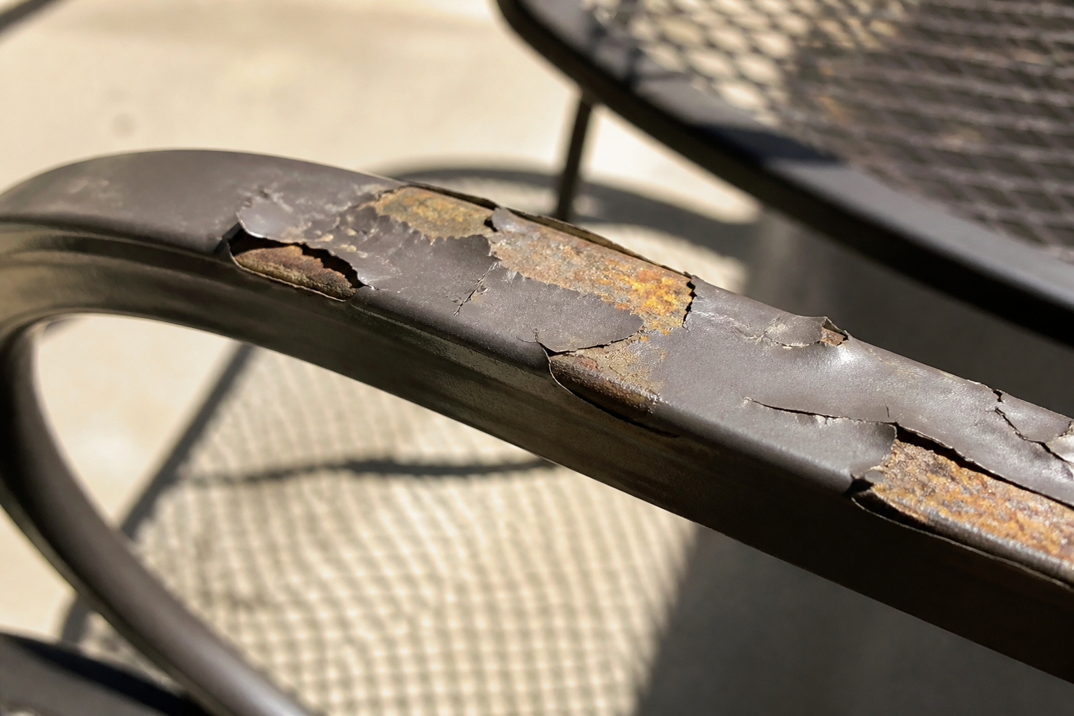 Addressing Hanamint Repair Challenges on a patio chair with peeling paint and worn fabric